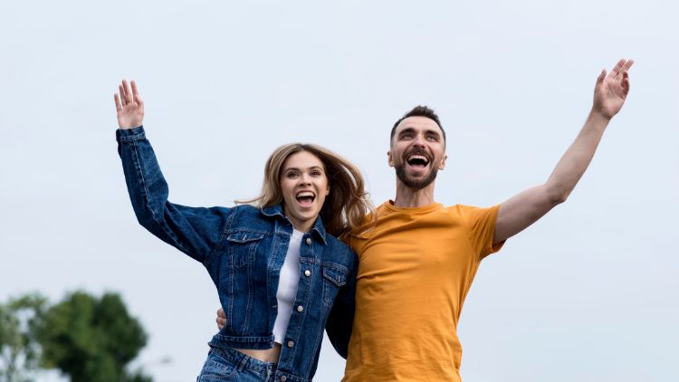 hombre y mujer felices alzando los brazos de alegria